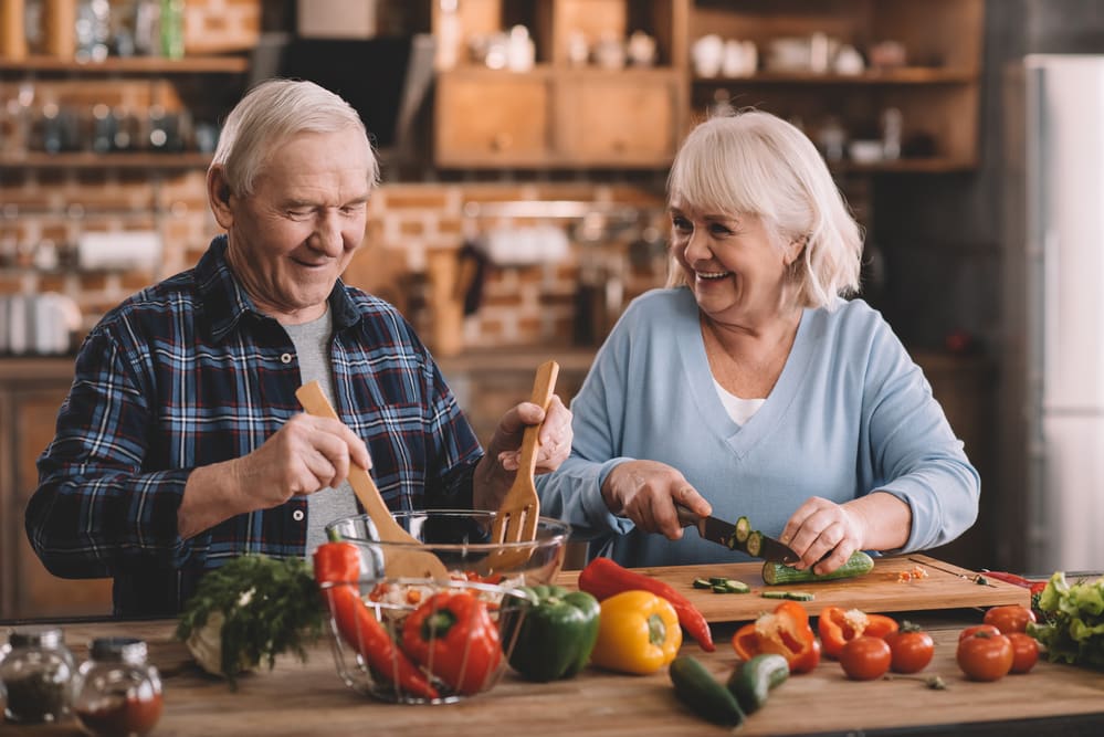 Smiling-senior-man-and-woman-preparing-vegetables-to-eat