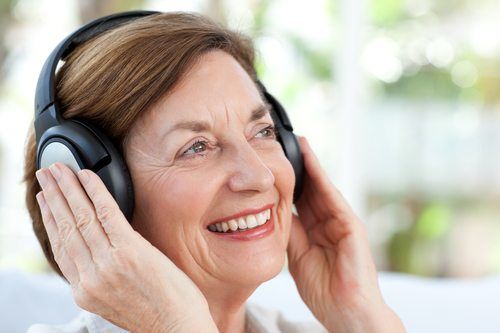 senior woman listening with headphones and smiling