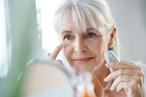 Portrait of senior woman applying facial cream