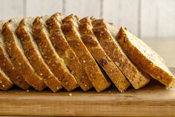 Loaf-of-whole-grain-bread-sliced-on-wood-cutting-board