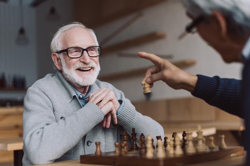 Senior-man-smiling-while-playing-chess-with-friend