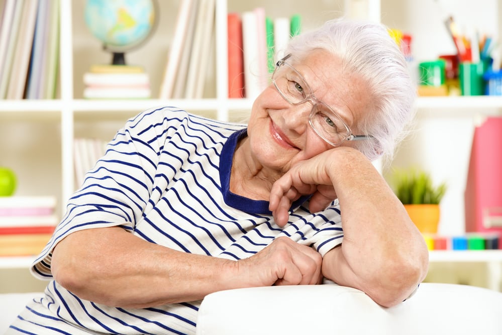 Senior-woman-on-couch-smiling-head-cocked-to-the-side