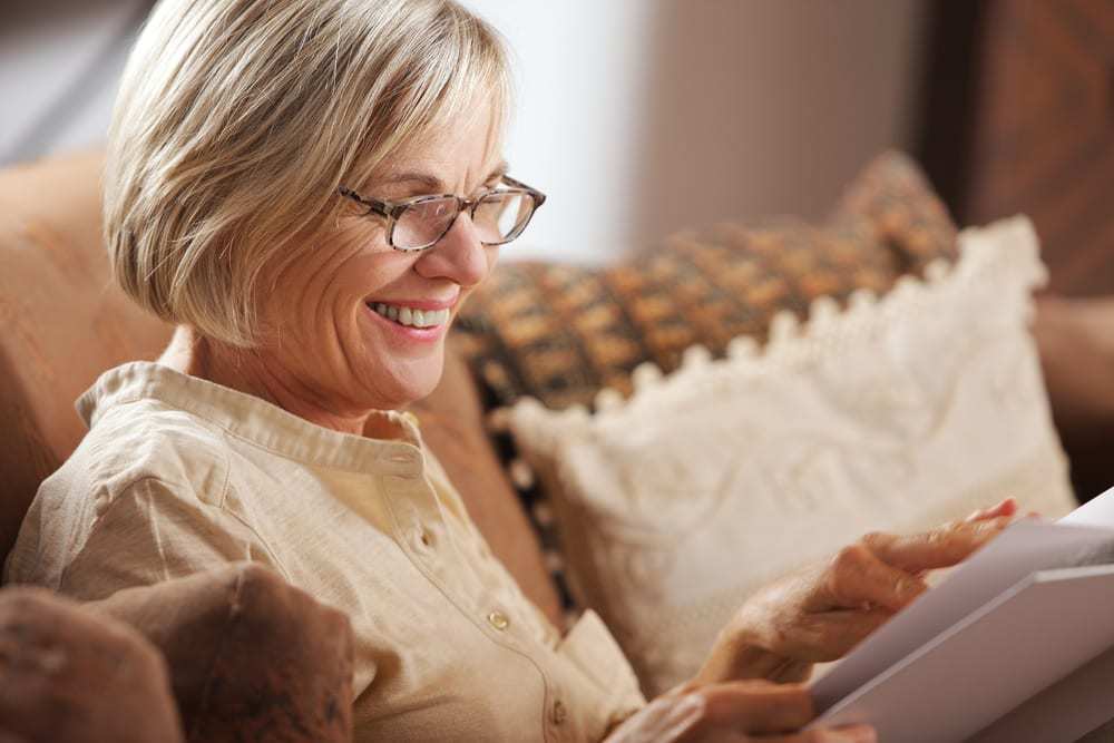 Senior-woman-reading-book-and-smiling