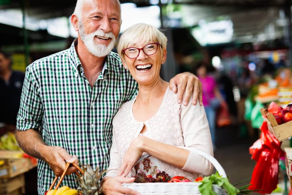 Smiling-senior-couple-buying-produce-at-farmers-market