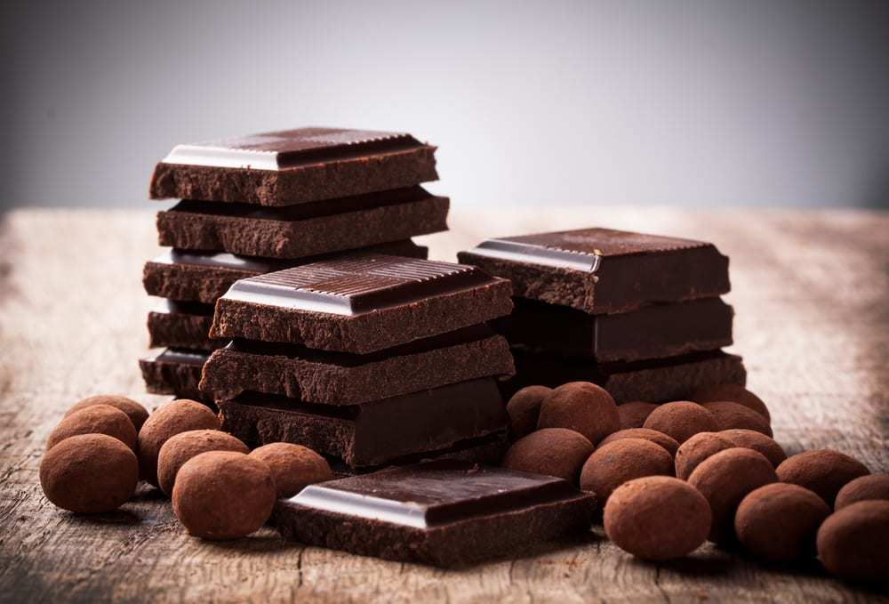Squares-of-dark-chocolate-in-stacks-surrounded-by-chocolate-covered-nuts