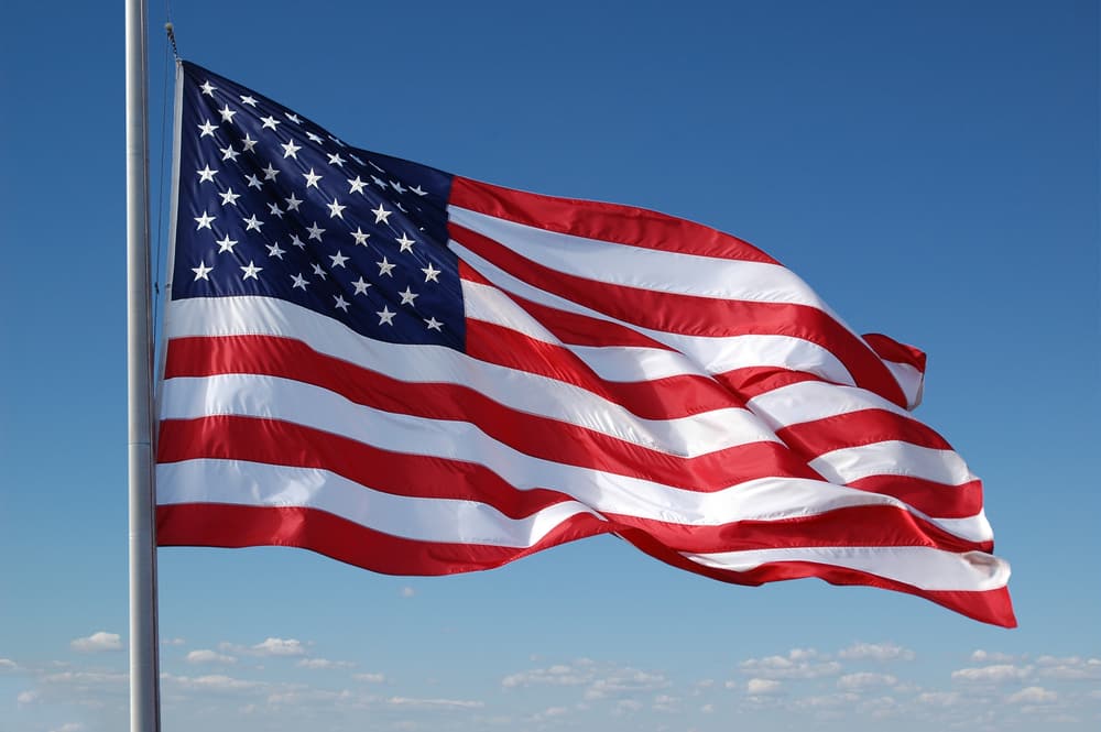 american flag flying in blue sky