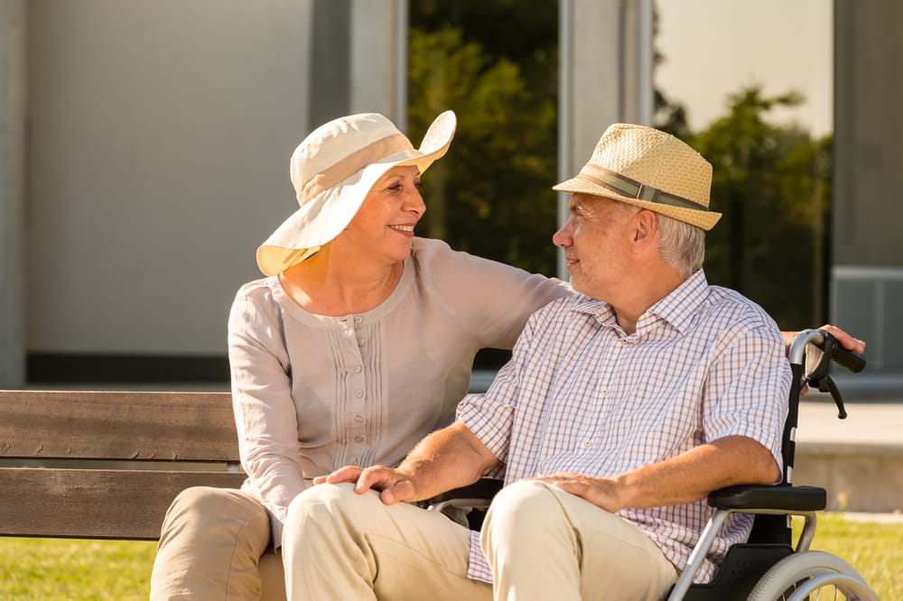 Senior man and woman talking outdoors wearing sunhats