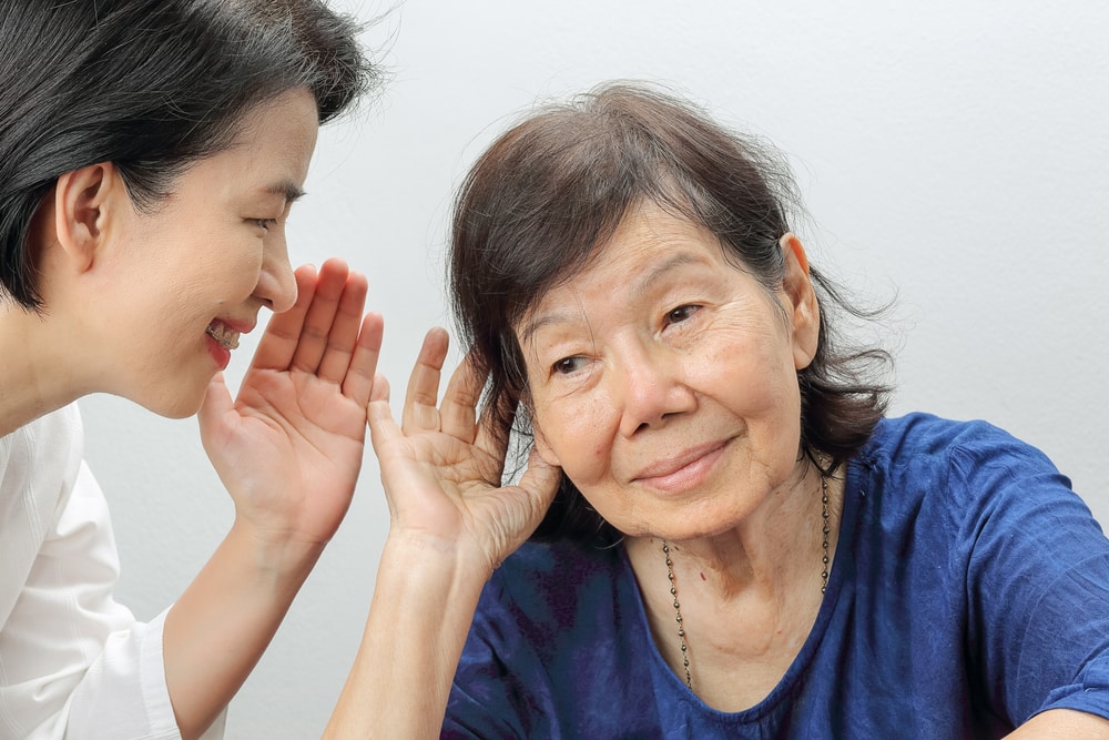 Smiling young woman whispering into the ear of senior woman