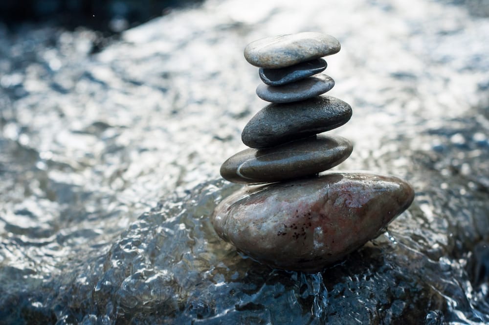 Stones balanced atop one another on rock in river