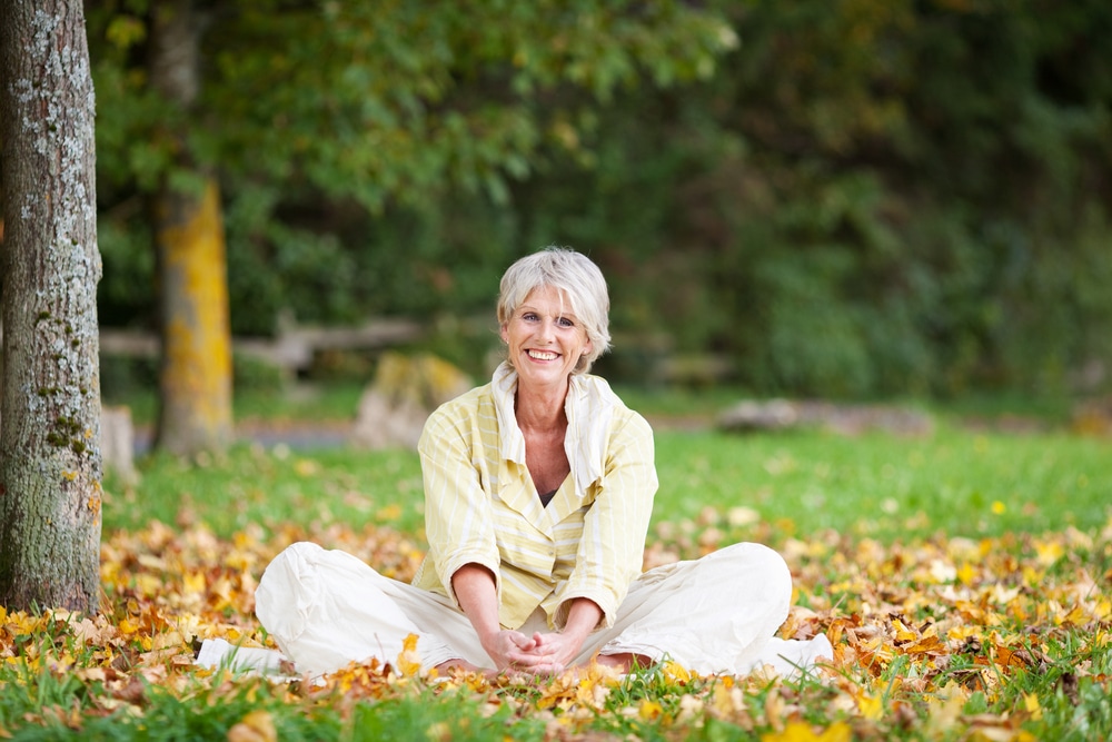 Smiling senior woman sitting outside in fall